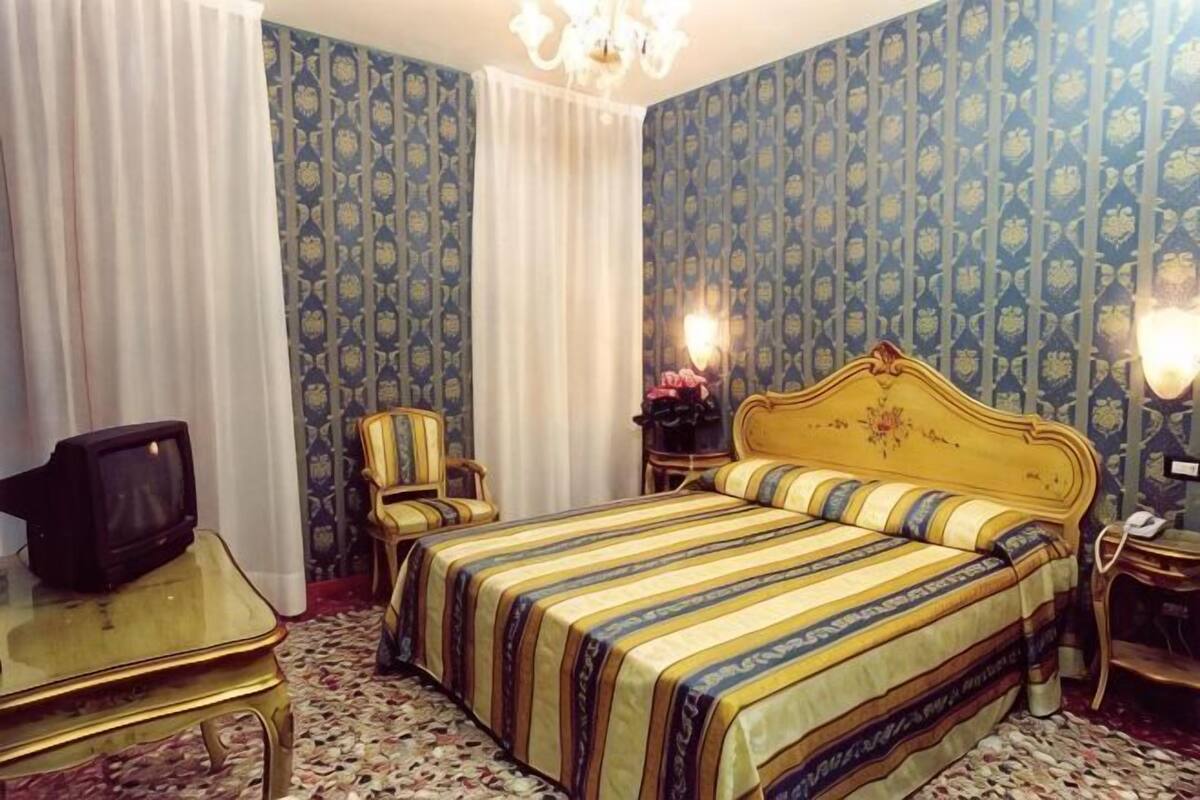 Una habitación de hotel con cama, televisión, silla y escritorio.