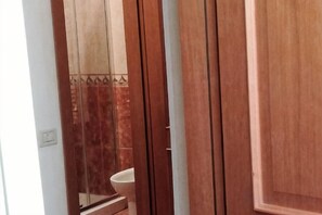 A bathroom with a toilet, a mirror, and wooden doors. - Hotel Il Mercante di Venezia (Venice)