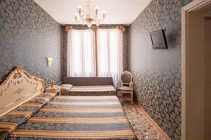 Un dormitorio con una cama grande, una mesita de noche, una silla y un televisor en la pared.