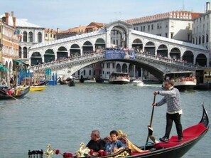 A gondola on a river with a bridge in the background. - Hotel Il Mercante di Venezia (Venice)