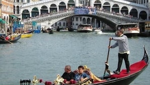 Una góndola en un canal con un puente al fondo.