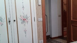 Una habitación con alfombra estampada, una puerta de madera y un interruptor de luz en la pared.