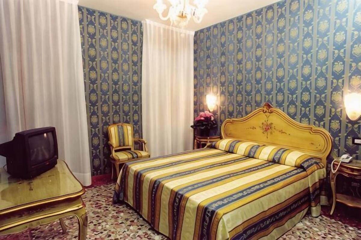 Una habitación de hotel con cama, televisión, silla y escritorio.