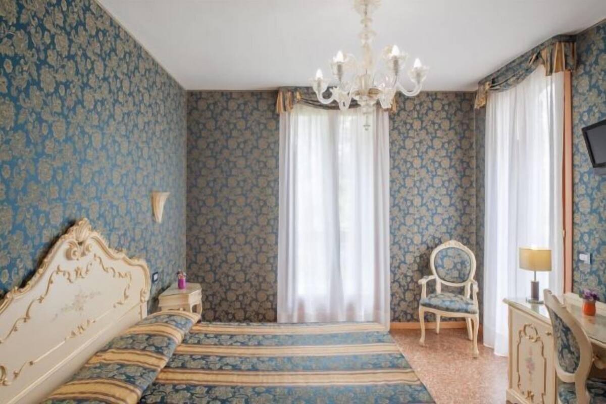 Un dormitorio con una cama, una silla, un escritorio y una araña.