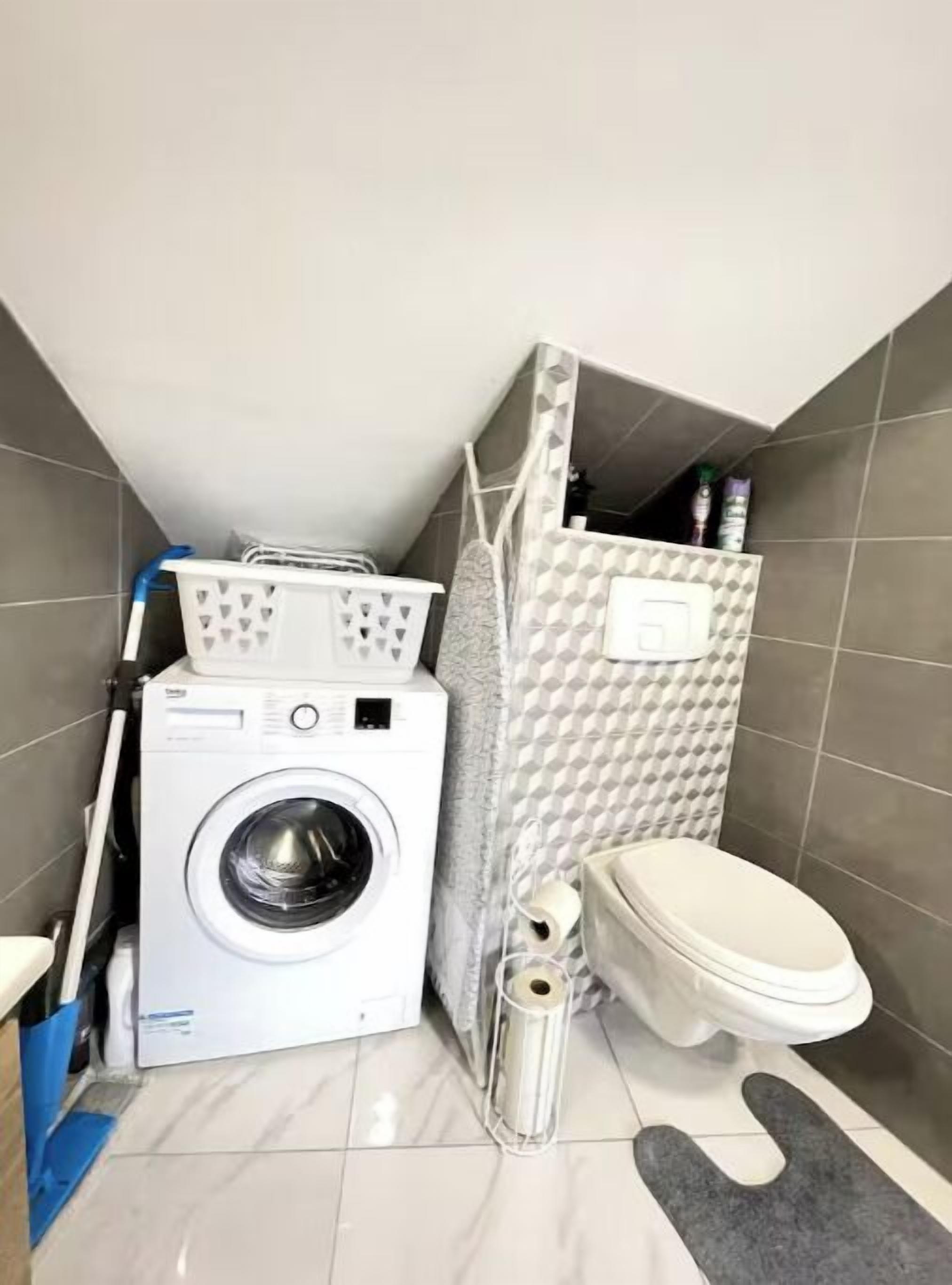 Un baño pequeño con lavadora, inodoro y un perchero para toallas.