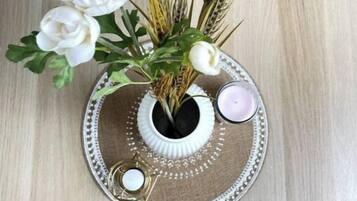 Un vase décoratif orné de fleurs blanches et de tiges de blé, posé sur un tapis texturé.