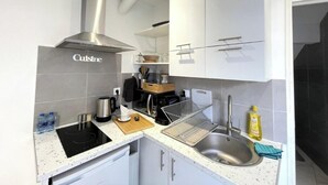 Une cuisine moderne avec des armoires blanches, une hotte de cuisinière en acier inoxydable et un plan de travail doté de divers appareils.