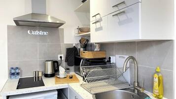 Una cocina moderna con un lavamanos de acero inoxidable, una cafetera y un hervidor.