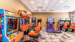 Une rangée de jeux d’arcade dans une pièce dont le sol est recouvert de carreaux et dont un des murs est uni.