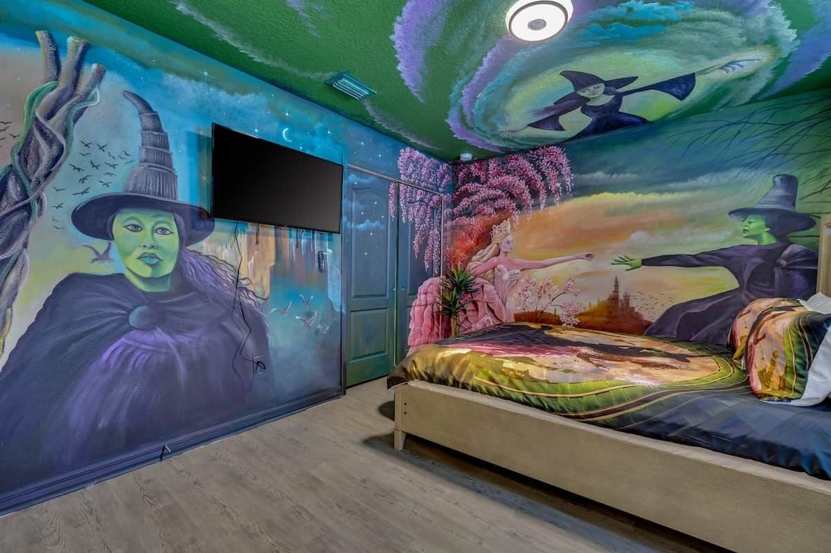 Una camera da letto con un affresco, un letto, una TV e una porta.