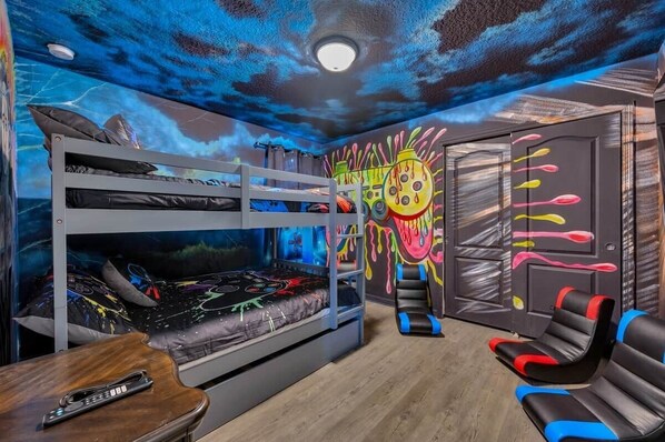 A bunk bed room with a mural, a desk, and a chair.