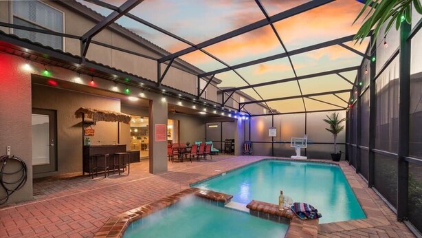 Un espace piscine intérieure doté d’un bar, de coins salon et offrant une vue sur le ciel.