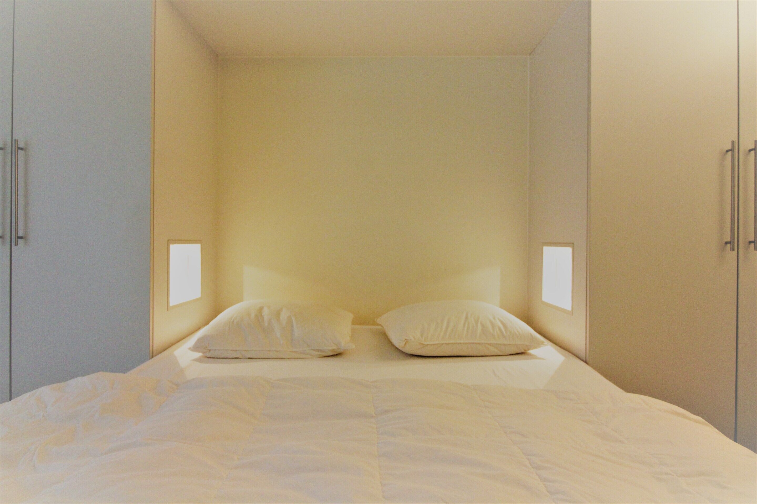 Ein Schlafzimmer mit einem Bett, zwei weißen Kissen und zwei Nachttischen mit Lampen.