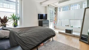 Una camera da letto moderna con un letto, una televisione, una cassettiera e una grande finestra.