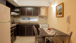 Una cocina compacta con armarios oscuros, estufa integrada y un comedor con mesa para dos.