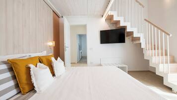 Una camera da letto moderna con un letto grande, una scala e una TV a schermo piatto montata a parete.