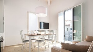 Una sala de estar moderna con un sofá, una mesa de comedor, sillas y un televisor.