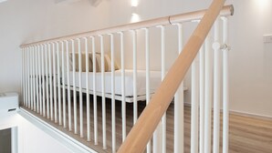 Una escalera blanca con barandilla de madera y pasamanos blanco.