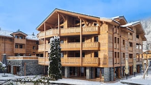 A multi-story wooden building with balconies, a stone base, and a sign reading "ICEBURG". - Wifi, 50m from resort center, 2nd floor, terrace, tv, ski locker, 82m², Les Gets (Les Gets)