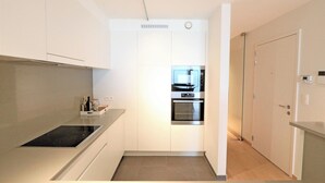 A modern kitchen with white cabinets, a built-in oven, and a stovetop.