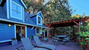 Una casa azul con terraza, mobiliario exterior y una pérgola.
