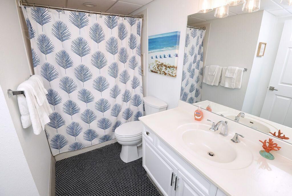 Un baño con cortina de ducha, inodoro, lavabo y espejo.