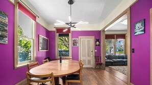 A dining area with a wooden table and chairs, purple walls, and a ceiling fan.