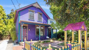 A two-story house with a purple exterior and a fenced front yard.
