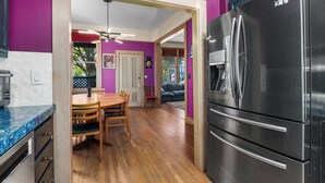 A modern kitchen with a stainless steel refrigerator, wooden dining table, and chairs.