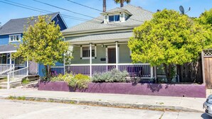 A two-story house with a front porch, a satellite dish, and a small tree.