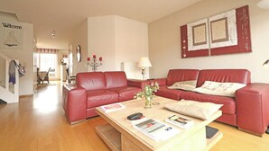 A living room with two red leather sofas, a wooden coffee table with magazines and a vase, and a wall with two framed pictures. - Duplex in Knokke Near North Sea Beach (Knokke-Heist)