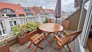 A wooden deck with a round table and chairs, surrounded by potted plants. - Duplex in Knokke Near North Sea Beach (Knokke-Heist)