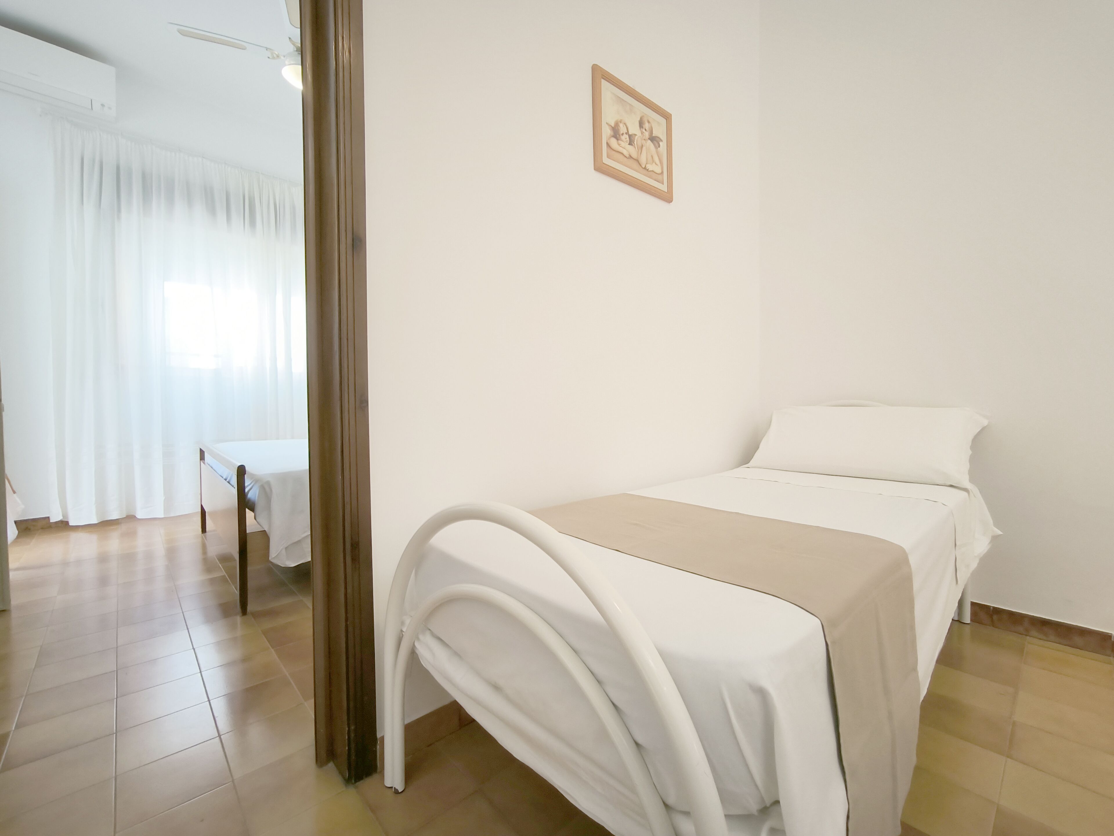 A clean, well-lit room with a bed, a small table, and a picture on the wall.