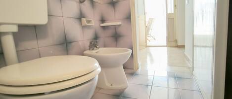 A bathroom with two toilets, a bathtub, and a shower.