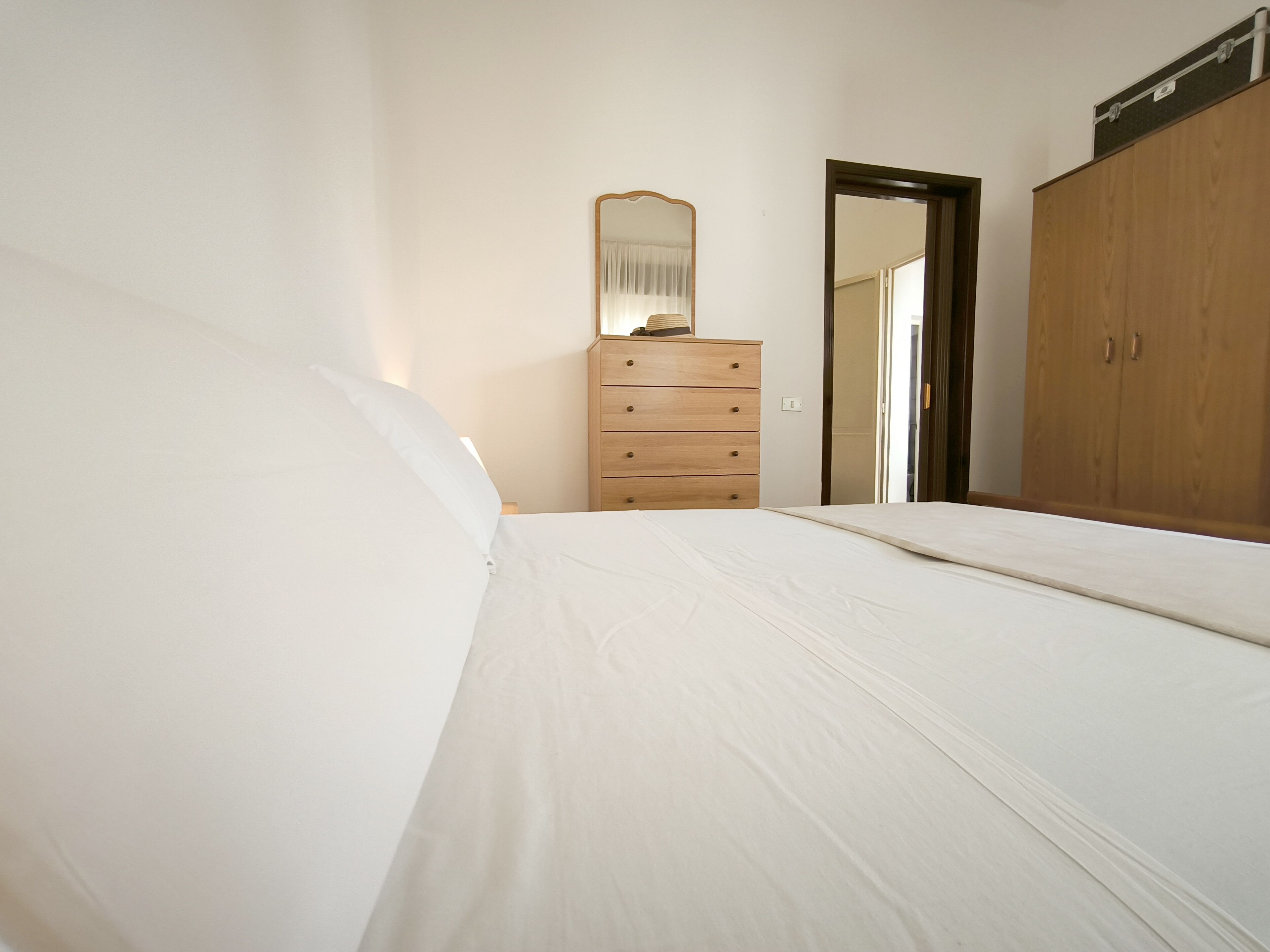 Ein Schlafzimmer mit einem Bett, einer Holzkommode und einem Kleiderschrank.