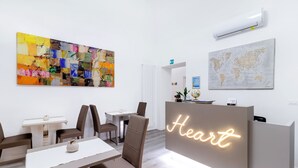 Ein Empfangsbereich mit einem Neonzeichen mit der Aufschrift "Heart", einer Weltkarte und einem farbenfrohen, abstrakten Gemälde.