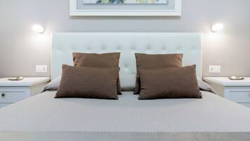A neatly made bed with a tufted headboard, two brown pillows, and a light-colored quilt. There are two bedside tables with a small lamp on each.