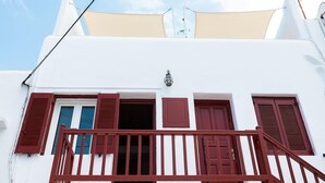 Un bâtiment blanc avec des volets rouges et un balcon.