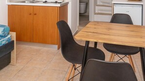 Une cuisine de taille réduite, dotée de meubles en bois, d’un évier et d’un coin repas avec une table et des chaises.