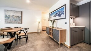 A modern kitchen with a built-in oven, a wooden dining table with chairs, and a large framed picture on the wall.