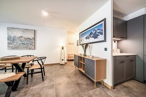 A modern kitchen with a built-in oven, a wooden dining table with chairs, and a large framed picture on the wall.