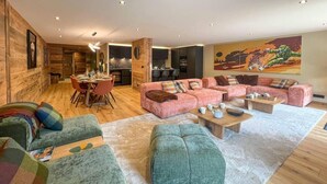 Un salon spacieux comprenant un grand canapé, un coin repas et une cuisine.