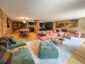 Un salón espacioso con un amplio sofá, una zona de comedor y una cocina.