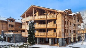 Un edificio de madera de varios pisos con balcones, una base de piedra y un cartel que dice 