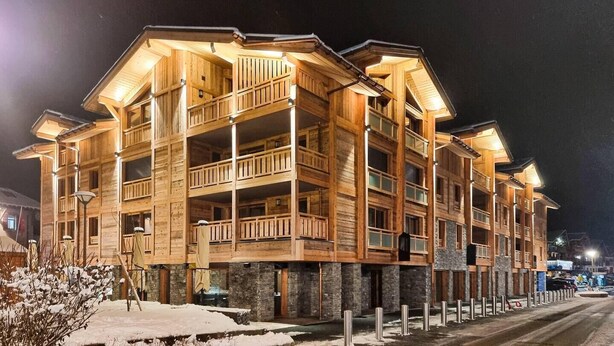 Un immeuble en bois à plusieurs étages, doté de balcons et fondé sur une base en pierre.