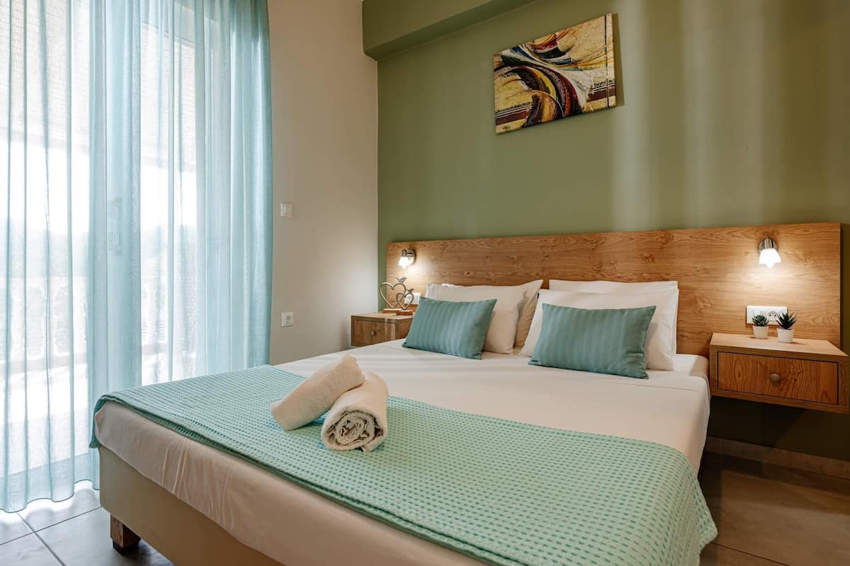 Une chambre d’hôtel avec un grand lit, une tête de lit en bois, deux tables de chevet avec des lampes et un tableau au mur.