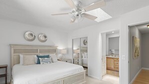 A bedroom with a large bed, a ceiling fan, and a walk-in closet.