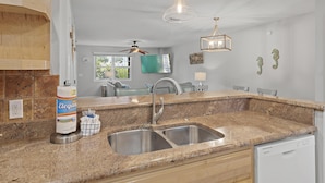 A kitchen with granite countertops, stainless steel sink, and a dishwasher.