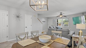 A dining area with a wooden table, white chairs, and a decorative bowl centerpiece.