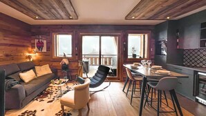 A cozy living room with a sofa, a coffee table, and a dining area with a table and chairs. There is a balcony with a view of the city.